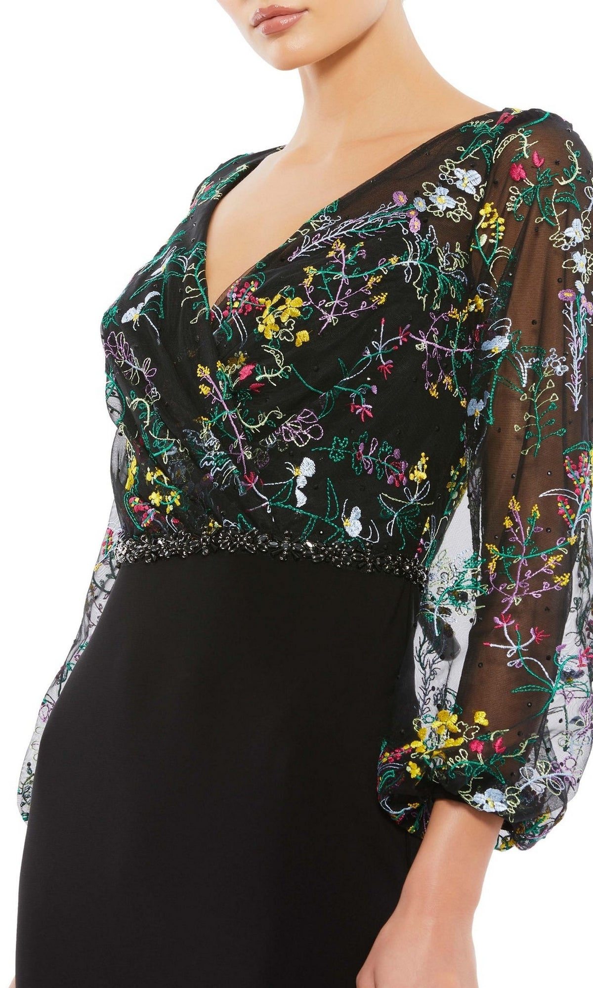 A woman wears the Mac Duggal 79379 long sleeve black formal dress, featuring sheer sleeves and multicolored floral embroidery on the bodice and sleeves—a stunning evening gown choice.